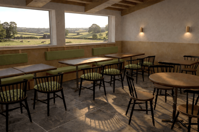 Contemporary café interior with wooden tables and chairs arranged beside large floor-to-ceiling windows overlooking greenery and countryside views. The space features warm natural materials, soft lighting, and a calm, modern atmosphere designed for dining and social interaction.