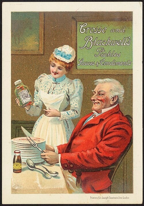 A late nineteenth-century advertisement for Crosse & Blackwell's pickles, sauces and condiments. A maid in a white apron presents a bottle of sauce to a smiling gentleman seated at a dining table, while a sign behind them promotes the company's range of preserved foods. The illustration reflects the growing commercial food industry, which made products such as pickles and preserves readily available to buy, reducing the need for households to produce them in their own still rooms.